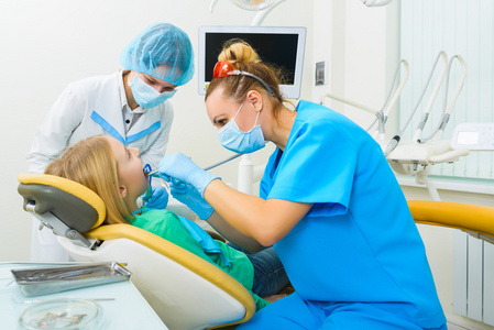 牙医和护士制作专业牙齿清洁女性年轻的病人，在牙科诊所