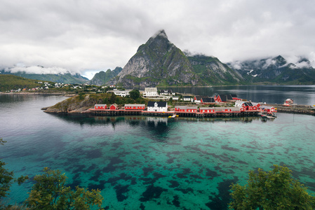 罗弗敦海岛屿与典型的红色钓鱼小屋和高耸的山峰上景区峡湾