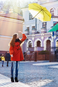 美丽的女人，黄色雨伞穿过城市