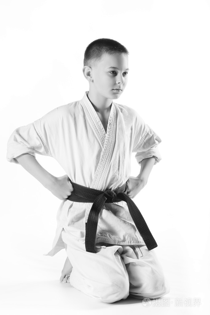 在和服在训练空手道练习在白色背景上的男孩
