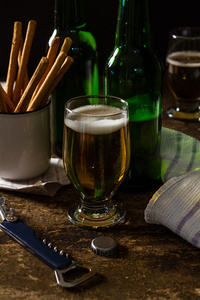 杯光啤酒与小吃的暗棕色的桌子上