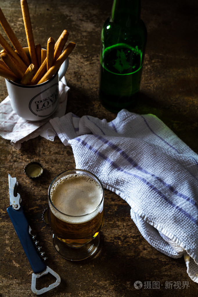 杯光啤酒与小吃的暗棕色的桌子上照片-正版商用图片1mgtmd-摄图新视界