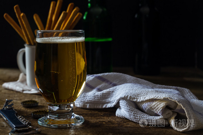 杯光啤酒与小吃的暗棕色的桌子上