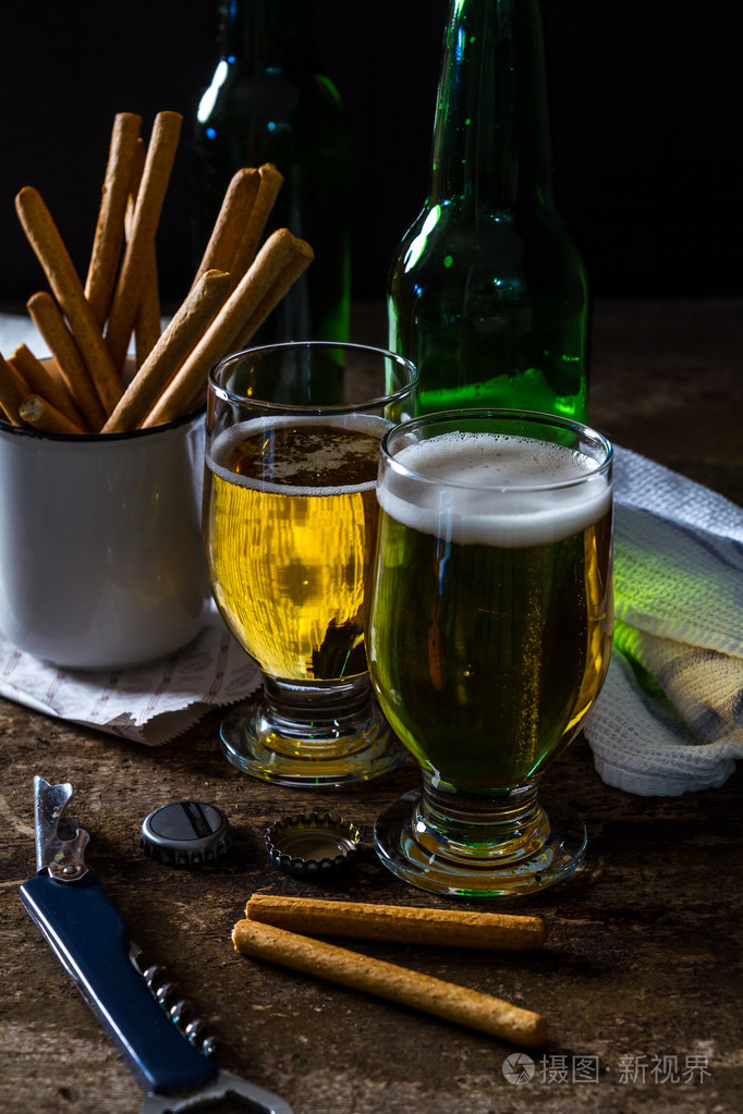 杯光啤酒与小吃的暗棕色的桌子上照片-正版商用图片1mguto-摄图新视界