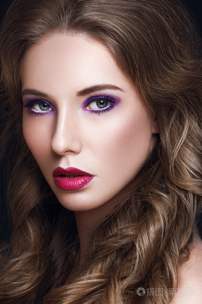 长长的棕色卷发的漂亮的模特女人化妆