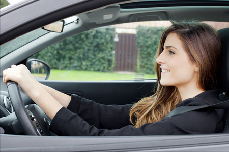 华丽的年轻女子,长头发,坐在车里开车微笑都很开心照片