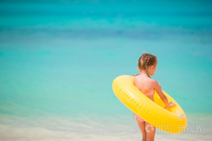 小女孩用充气橡胶圈在海滩度假的肖像