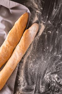 两个法国面包用面粉的黑暗背景上