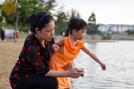 亚洲母亲和女儿喂鱼
