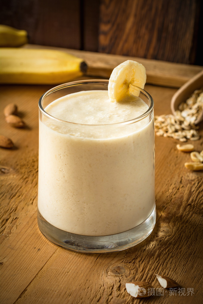 在木制的桌子上的玻璃内的坚果香蕉酸奶思慕雪
