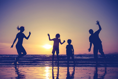 幸福的家庭的剪影在一元在沙滩上玩的人