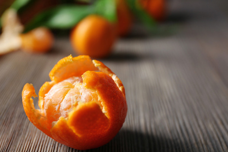 去皮新鲜橘红色和叶与成熟柑在木桌子上，特写