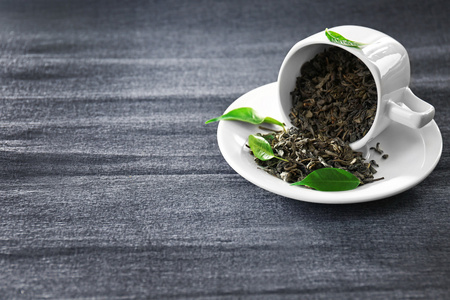 绿色的叶子中套茶具在灰色的背景上茶颗粒