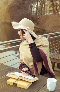 漂亮法国黑发女人帽子和雨披等待春天湖附近