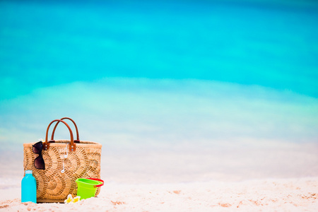 海滩配件稻草袋 防晒霜瓶和在海滩上的红色太阳镜