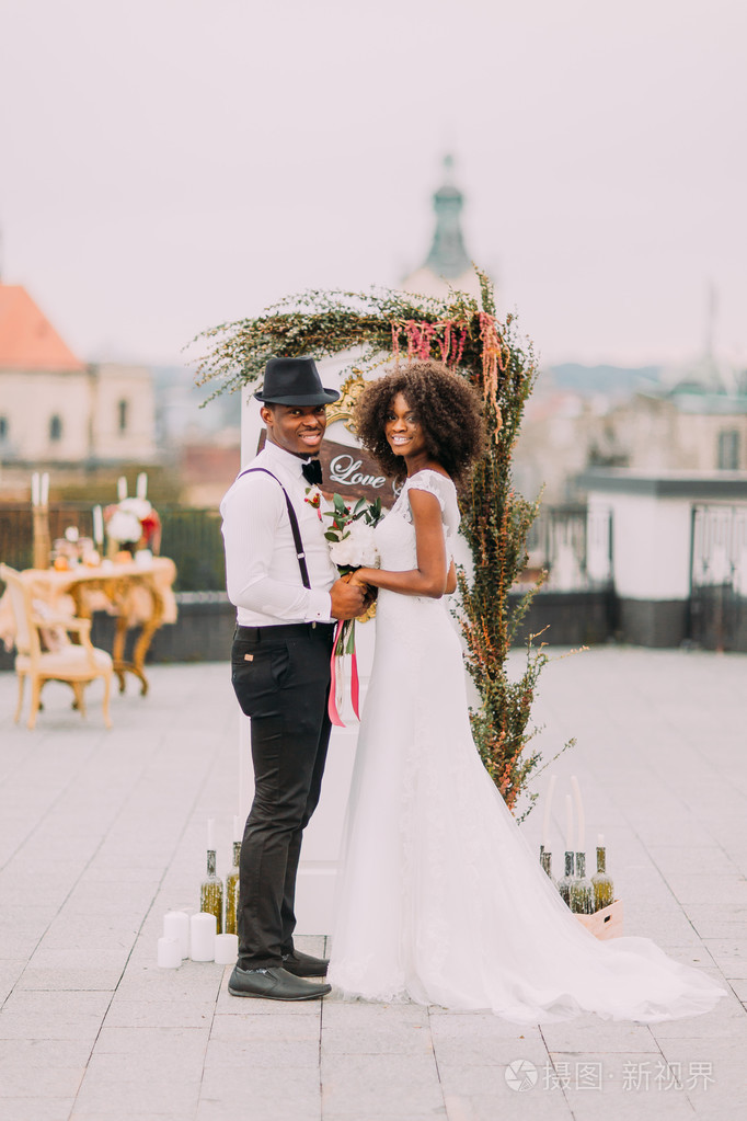 happy african bride and groom posing for camera and smiling on t