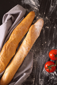 两个法国面包用面粉的黑暗背景上