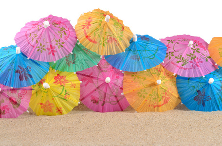 五颜六色的纸鸡尾酒雨伞在沙子特写在白色