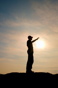 游客在触摸到太阳的徒步旅行者站在国家公园的砂岩岩峰上的红色棒球帽