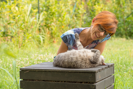 在绿色家庭花园里玩猫的女人