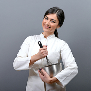 美丽的女厨师混合在一个碗里反对灰色 b 的肖像