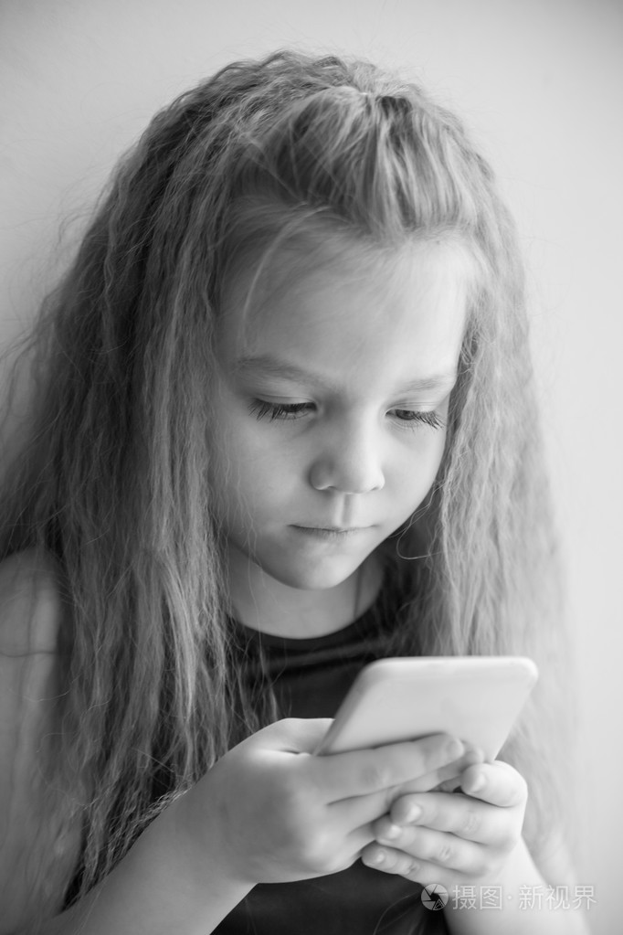 小女孩盯着智能手机