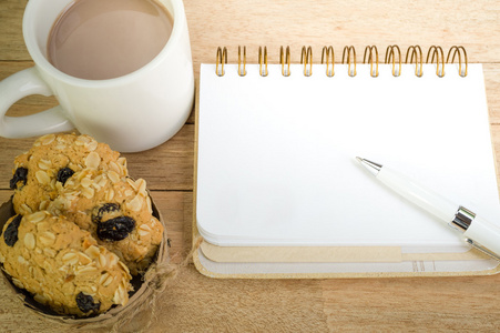与咖啡和燕麦饼干上木背景空白笔记本