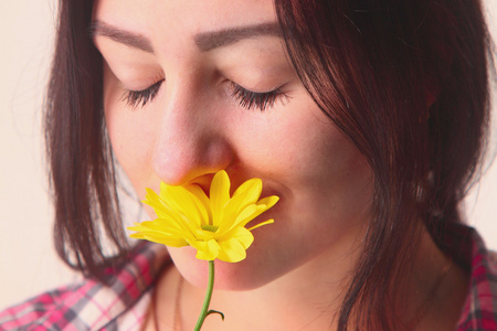 肖像年轻女孩闻黄朵花