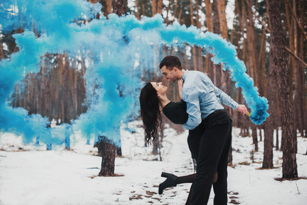 夫妇在冬季森林与彩色烟雾中拥抱