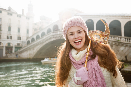 微笑的女人拿着威尼斯面具在里尔托桥前面