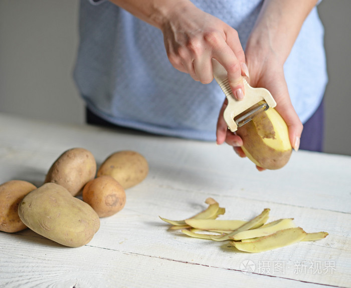 女人的手煮马铃薯削皮