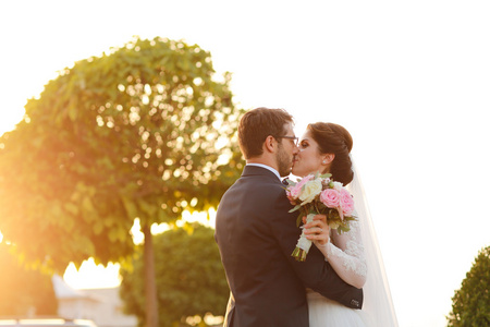 快乐的新娘与新郎同拥抱在户外的花束