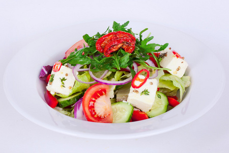 希腊沙拉黄瓜羊乳酪百里香，红洋葱，晒干的番茄板分离白色背景芝麻菜
