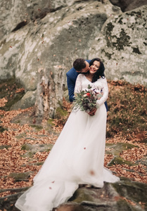 华丽的新娘，新郎亲吻和拥抱附近的悬崖美景