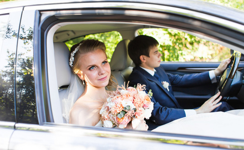 新娘和新郎在车里。他们很高兴