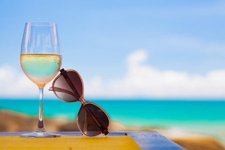 冷冻的白酒和太阳镜在海滩附近的桌子上的玻璃