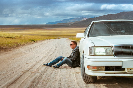 一个男人在附近的车上白色背景干草原和高山