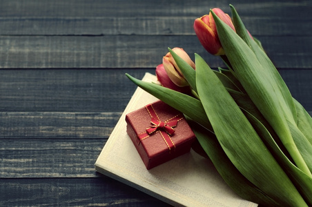 郁金香 书和礼品木制表面的红盒子