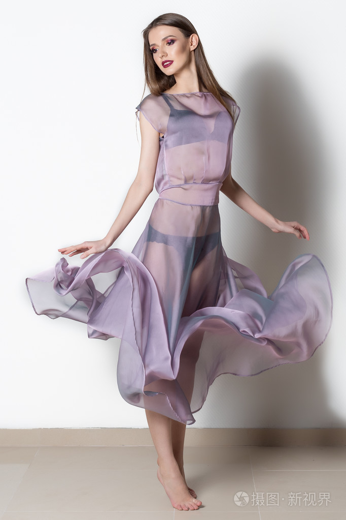 亮妆在工作室中流动的透明装的梦幻般的时尚女人