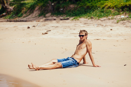 轻松的男人一个热带的海滩。年轻晒黑的人服用 sunbat