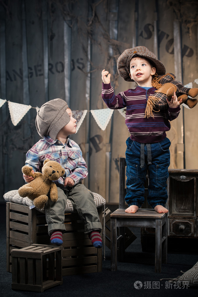 两个小男孩在帽坐在工作室中的框上大约如此