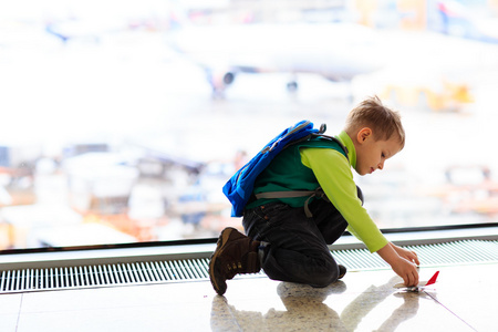 小男孩玩玩具架飞机在机场
