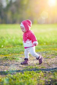 快乐的小女孩走在草地上，看着太阳