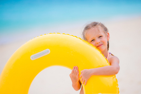 充气橡胶圈准备游泳的白色沙滩上的可爱女孩