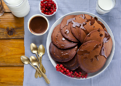 用木制的桌子上的巧克力糖浆的巧克力薄饼。成熟