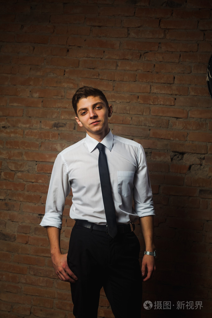 时尚帅气年轻男模白色砖墙前摆姿势