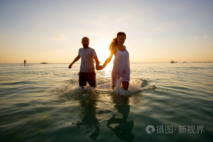 浪漫的情侣在七彩的晚霞，在海滩上背景