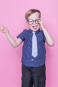 小可爱的男孩在领带和眼镜。学校。学前班。时尚。工作室画像在粉红色的背景