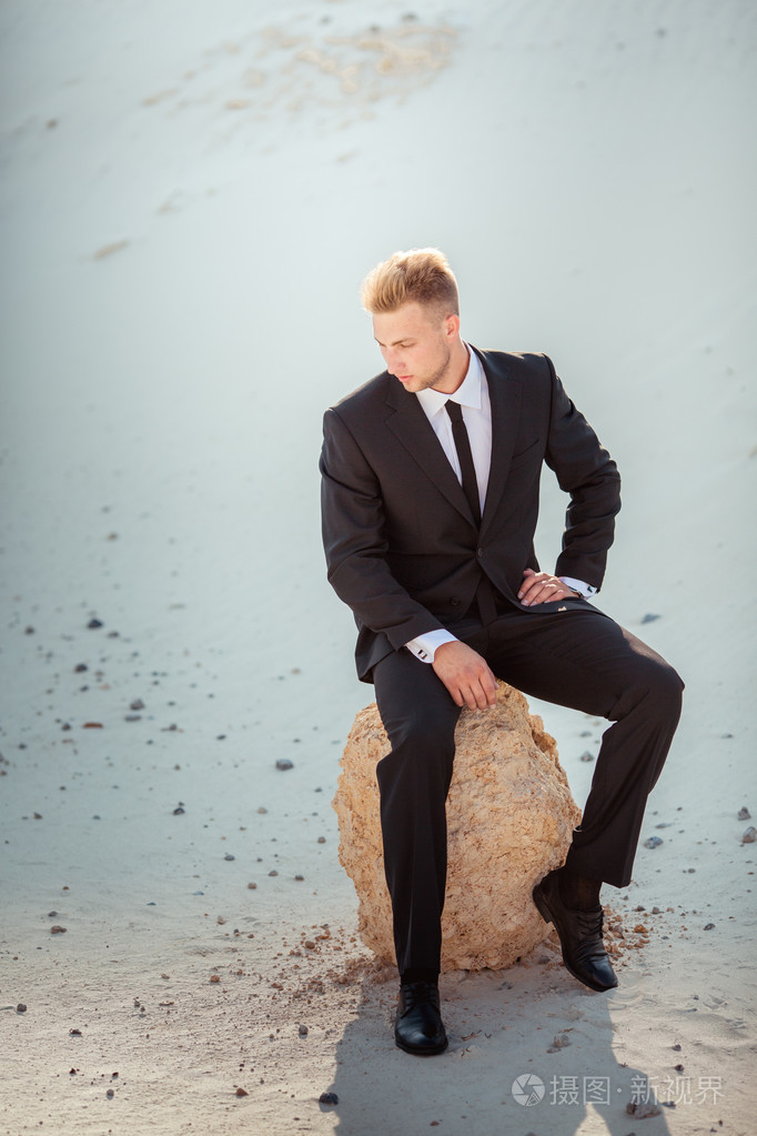 坐在石头上的黑色西装的商人