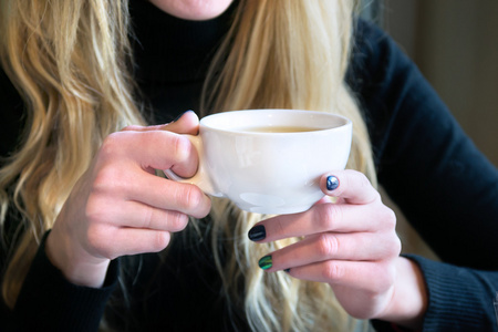 捧着杯茶的一家咖啡馆的女人